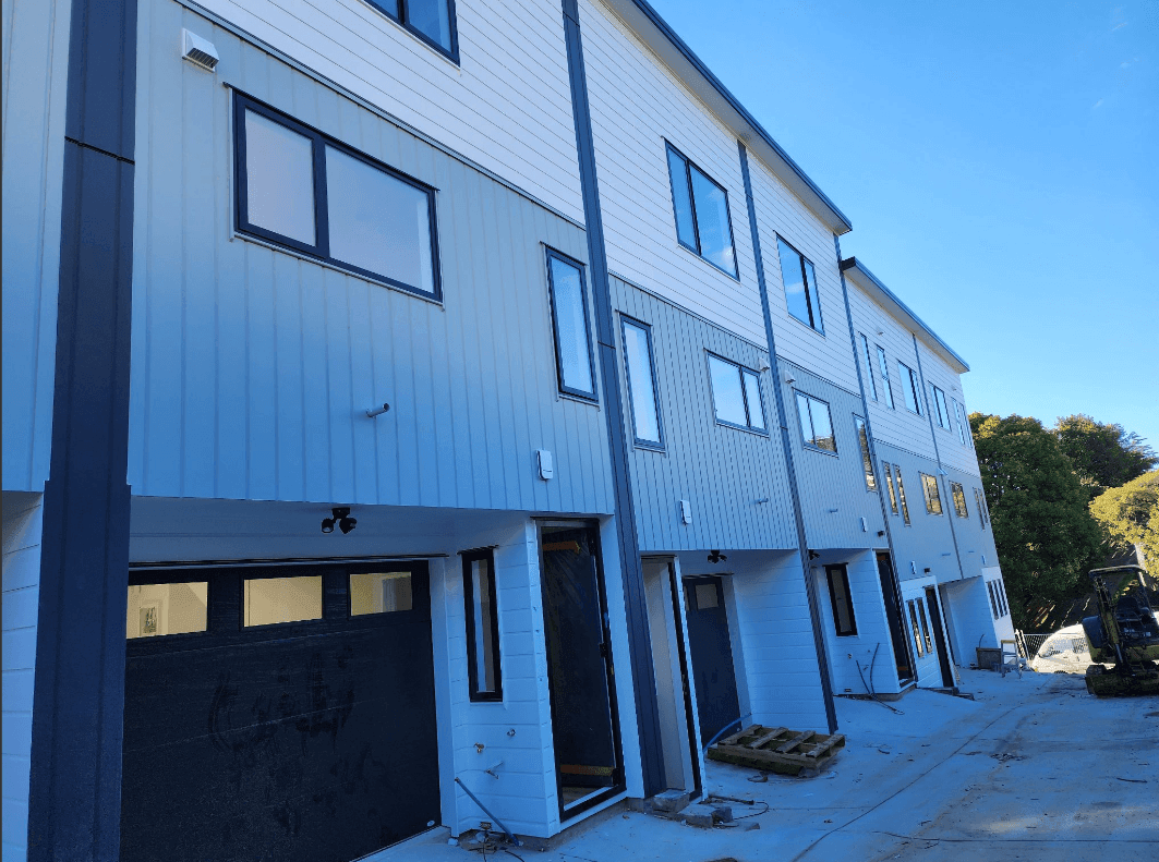 Row of newly constructed three-story townhouse units with garage doors on the ground floor.