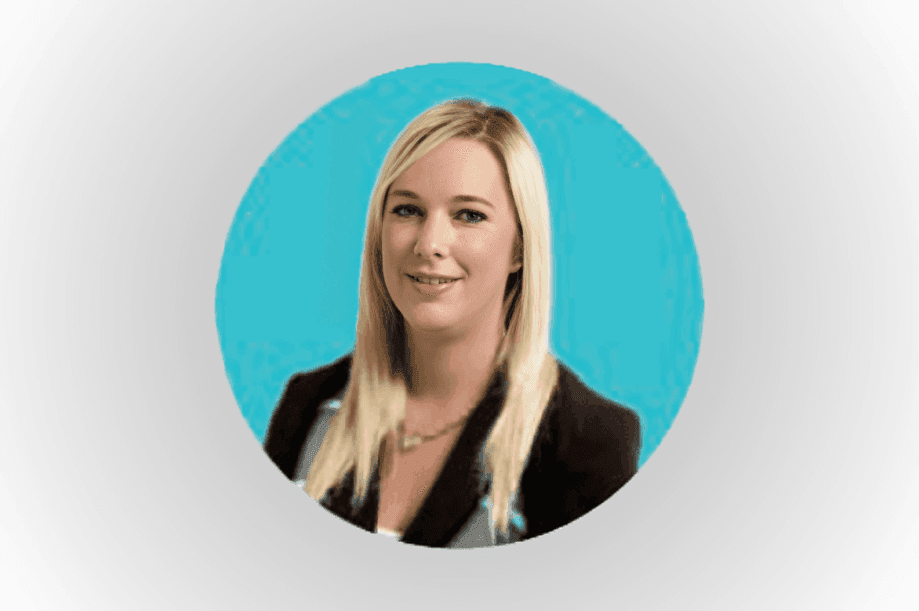 Portrait of a smiling woman with blonde hair wearing a black blazer, against a blue background.