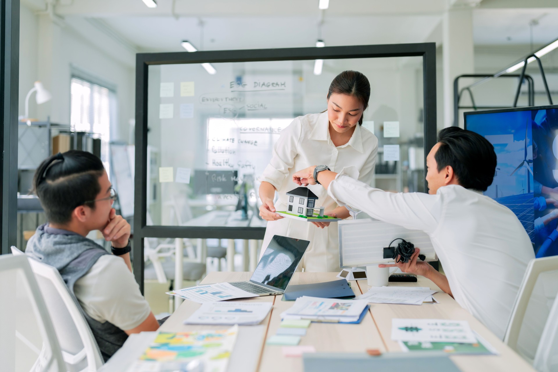 A team of professionals collaborates in modern office, discussing model house. atmosphere is focused and creative, showcasing teamwork and innovation